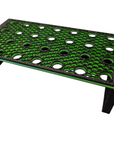 The AO - Coral Frag Rack - Finished End - Petg is a rectangular black stand made of durable PETG, featuring a perforated grid with circular holes, a dovetail design, and a green underside. It includes four legs to securely elevate an object above the surface.
