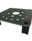 The AO - Skimmer Stand/Platform is a black and green perforated square platform with sturdy, slightly angled legs. It features multiple circular holes on the surface and a central larger opening, designed for supporting or elevating objects.