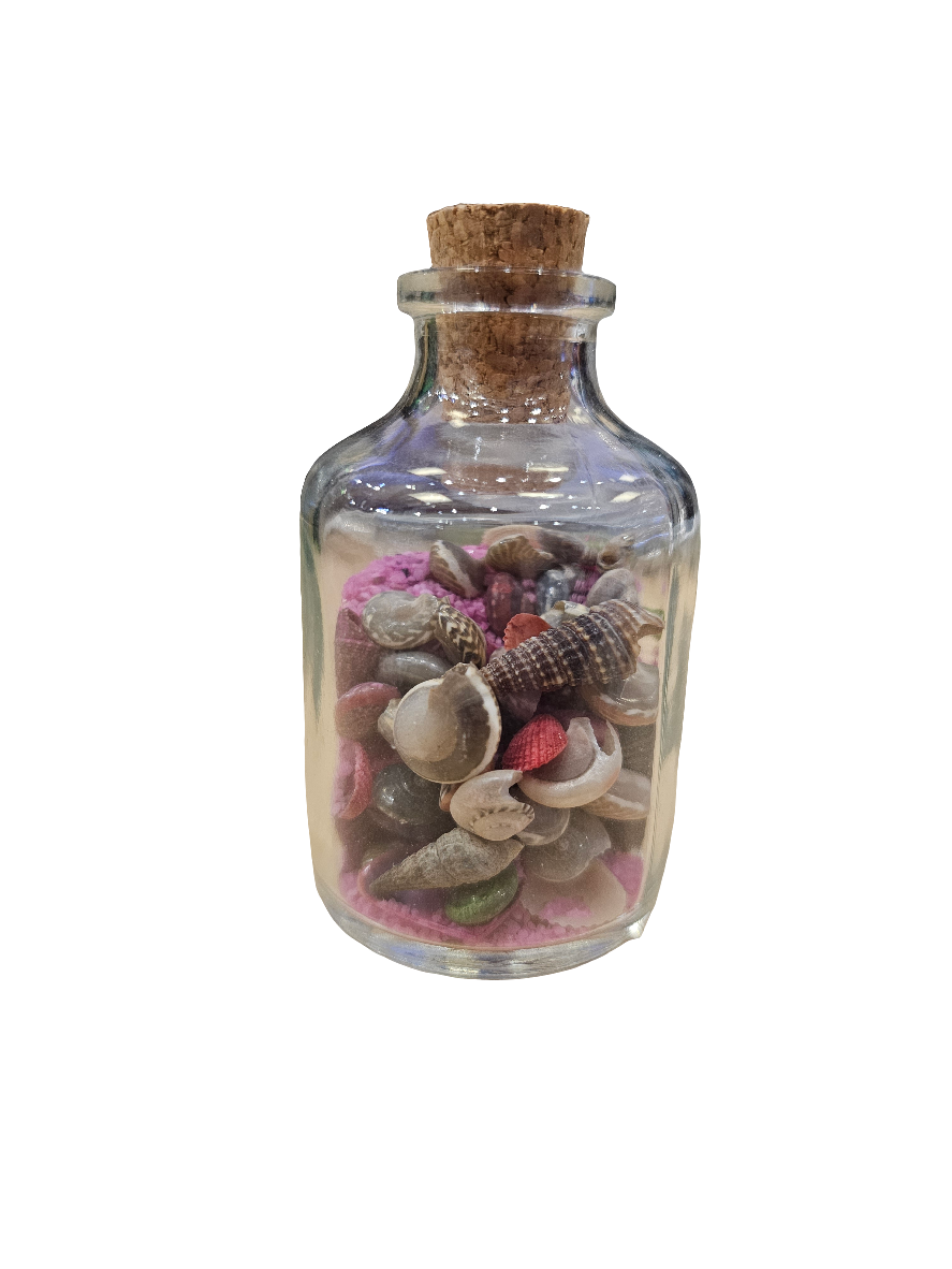 A small glass bottle with colored sand and shells, featuring a cork lid, sits against a white background.