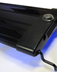 Close-up of the Aquarium Masters - Advance LED Lighting Systems 48 in black, showcasing its sleek rectangular design and LED technology for optimal color rendition. It features a circular button and vent-like slots at one end, with two metal hooks on the edges and a soft blue glow from below.