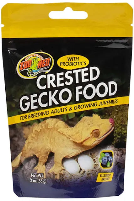 Image of a Zoo Med - Crested Gecko Food Breeder 2oz bag with probiotics for breeding adults and juveniles. The black and yellow package displays a crested gecko and blueberries. Net weight: 2 oz (56 g).