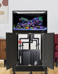 A 112-gallon Innovative Marine INT Lagoon Aquarium, filled with vibrant coral and rocks, features an open cabinet and filtration equipment. It sits in a modern room with wooden floors, a red armchair, and minimalist wall art.