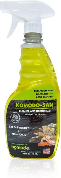 The image displays a yellow spray bottle labeled Komodo - San Cleaner & Deodoriser Spray 16 Oz, ideal for terrariums and small reptile cages. Easy to apply, its safe for reptiles, eco-friendly, and non-toxic. A U.S. flag in the bottom right corner emphasizes its origin.