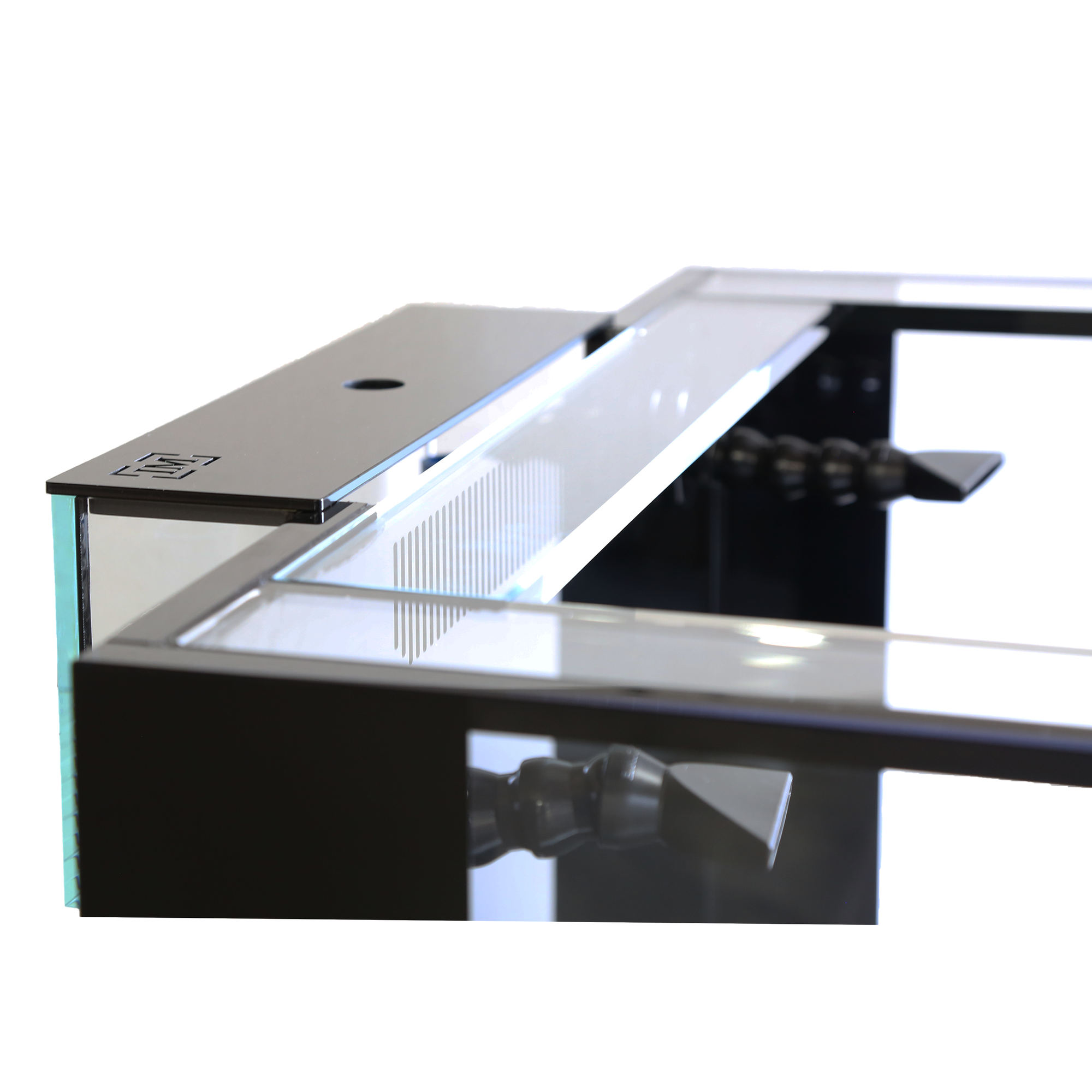 Close-up of a modern desk with a sleek black metal frame and glass top, similar to the Innovative Marine EXT 200 Peninsula Aquarium w/ APS Stand. The corner is highlighted, showing a mounting bracket and adjustable levers underneath, reminiscent of setting up this made-to-order model.