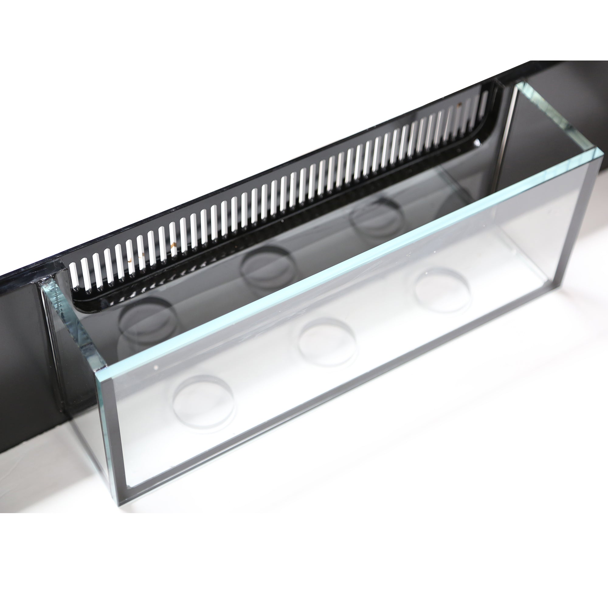 The Innovative Marine - EXT 170 Aquarium w/ APS Stand features a clear acrylic overflow box with a comb-style top, circular cutouts for water passage, and integrates seamlessly with the Bean Animal drain system against a black background for efficient aquarium filtration.