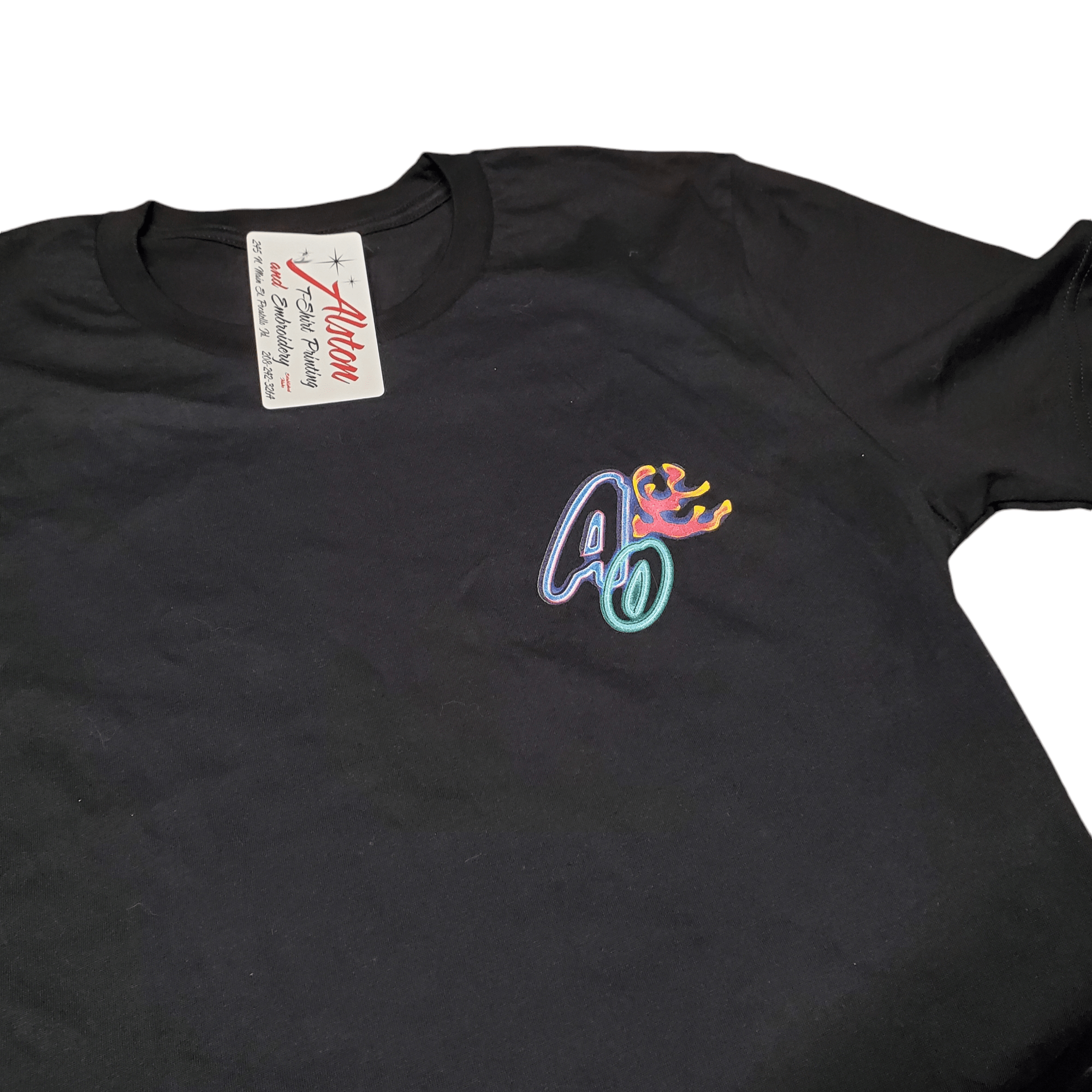 A black AO - Aquatic Oasis Shirt featuring a vibrant embroidered design with the letters A and O topped with a crown on the chest area, labeled by Allen Branding.