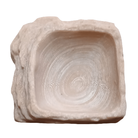 Close-up of the AO - Reptibowl Sml, showcasing its square shape and cream color with a textured, spiral pattern inside. The bowl features a rough outer surface contrasted by a smooth inner surface.