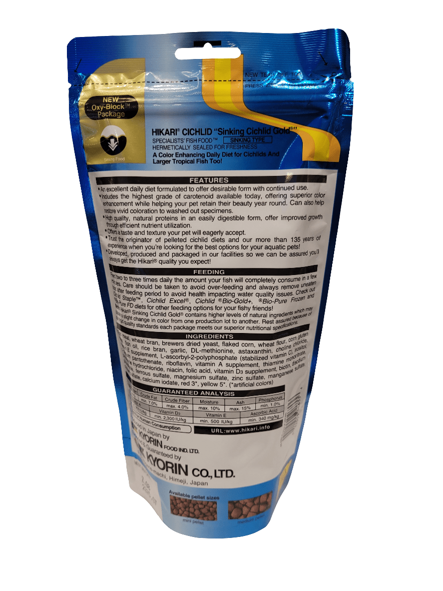 The image displays a package of Hikari - Cichlid Gold - Mini Sinking fish food in a blue and white bag. The back is visible, showcasing detailed product information, feeding instructions, and manufacturer details. Brown pellets can be seen through a clear section on the bottom of the package.