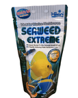 A 3.52oz package of Hikari Seaweed Extreme fish food for marine herbivores, adorned with an image of a yellow fish, boasts a 67% seaweed content and is designed to promote growth and form in fish.