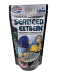 An 8.8oz package of Hikari Seaweed Extreme Med Sinking Pellet fish food, designed for marine herbivores, features colorful images of vibrant fish on the pouch. The packaging highlights key benefits such as growth-promoting ingredients, with 67% seaweed content and rapidly softening pellets.