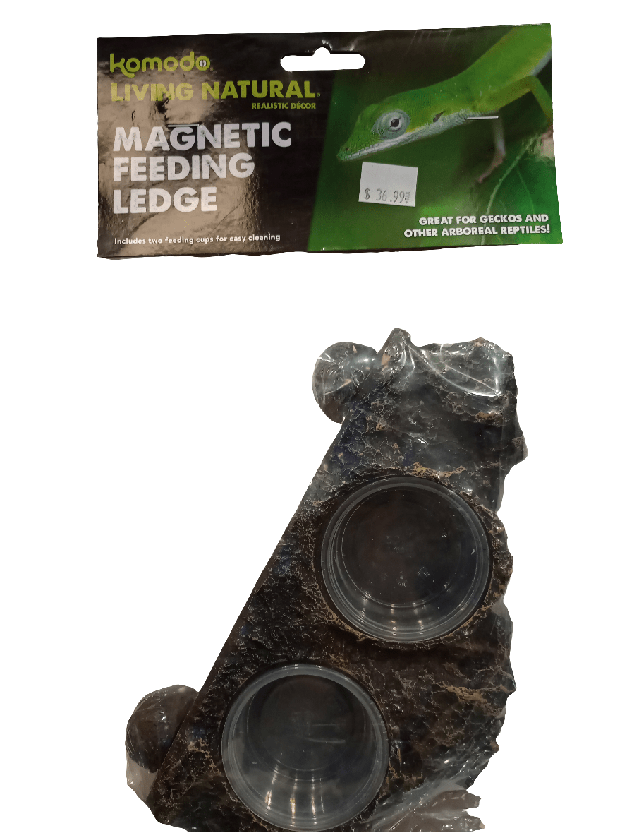 The packaging for the Komodo Magnetic Feeding Ledge showcases a realistic rock design. It comes with two feeding cups and is targeted towards geckos and other arboreal reptiles, with the price tag displayed in the top right corner.