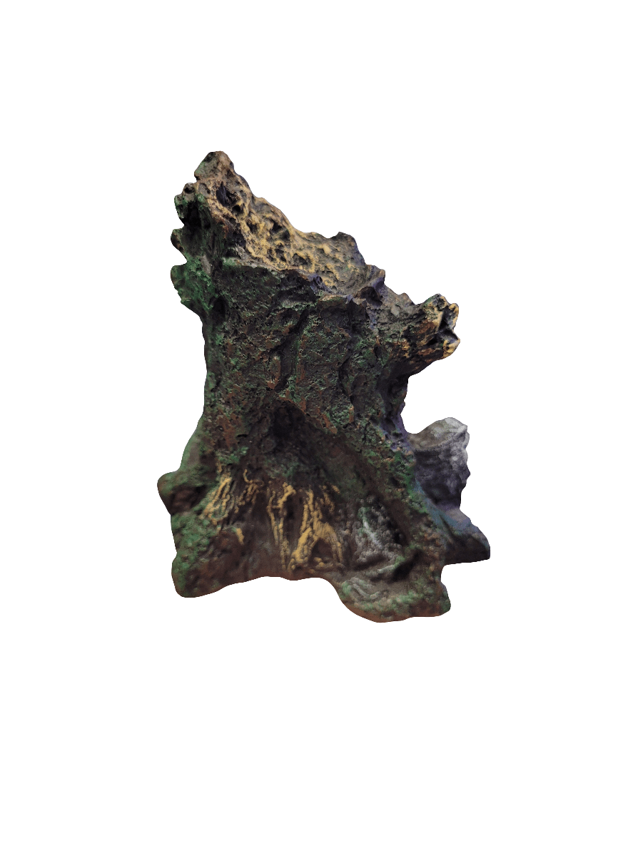 The Komodo - Nano Forest Daintree Decor features a textured, dark brown and green rock formation with jagged edges and a rough surface, set against a plain white background.