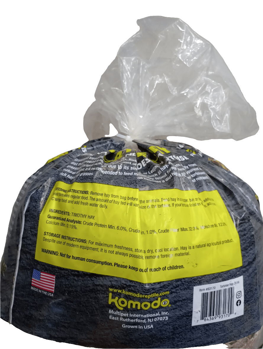 A 24oz plastic bag of Komodo - Tortoise Hay. The packaging provides feeding instructions and nutritional information, manufactured by Muepet International, Inc., featuring an American flag symbol to show it is made in the USA.