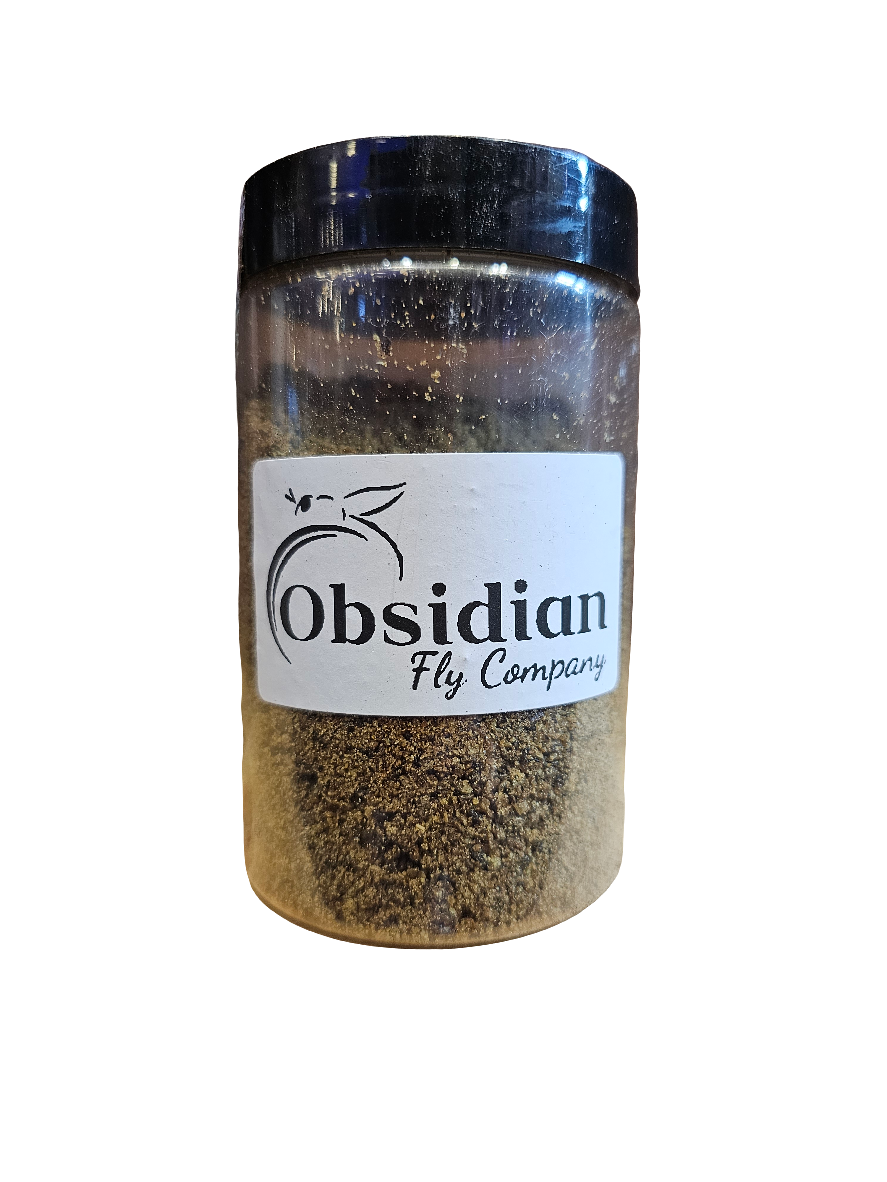 A clear jar with a black lid contains brown powder and is labeled Obsidian Fly Co. - Black Soldier Fly Larvae - Larval meal 3 oz, featuring a fly graphic above the text.