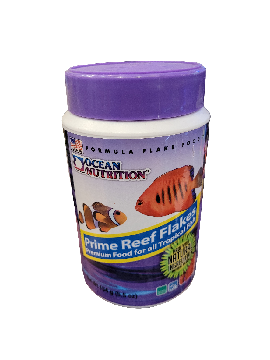 A 5.5oz container of Ocean Nutrition Prime Reef Flakes fish food features a label with colorful fish images, text stating its premium food for all tropical fish using natural ingredients, and a purple lid.