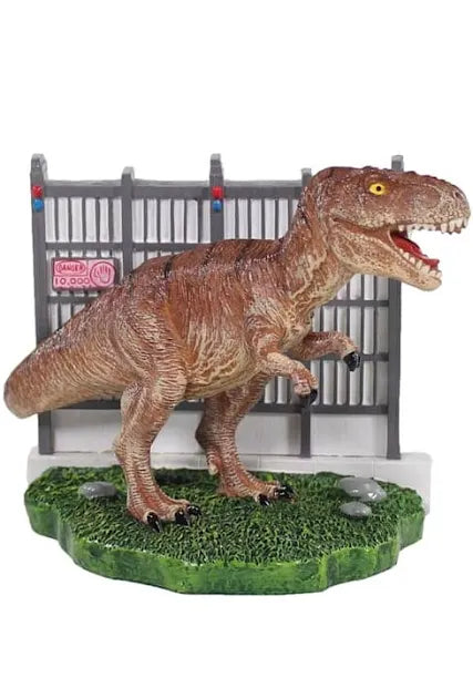 The PennPlax - Jurassic Park - T. Rex Decor Sml is depicted in front of a gray fence adorned with warning signs, showcasing its brown textured skin and fierce expression while posed with one foot on a grassy base.