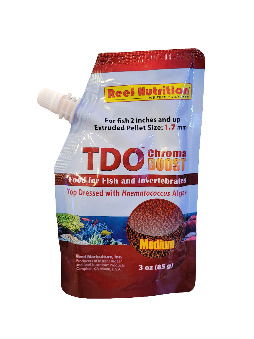 The image displays a pouch labeled "Reef Nutrition - TDO Chroma Boost," featuring Medium Pellet fish and invertebrate food. The package has a red-and-white design, highlights the inclusion of Haematococcus Algae, and specifies the weight as 85g.