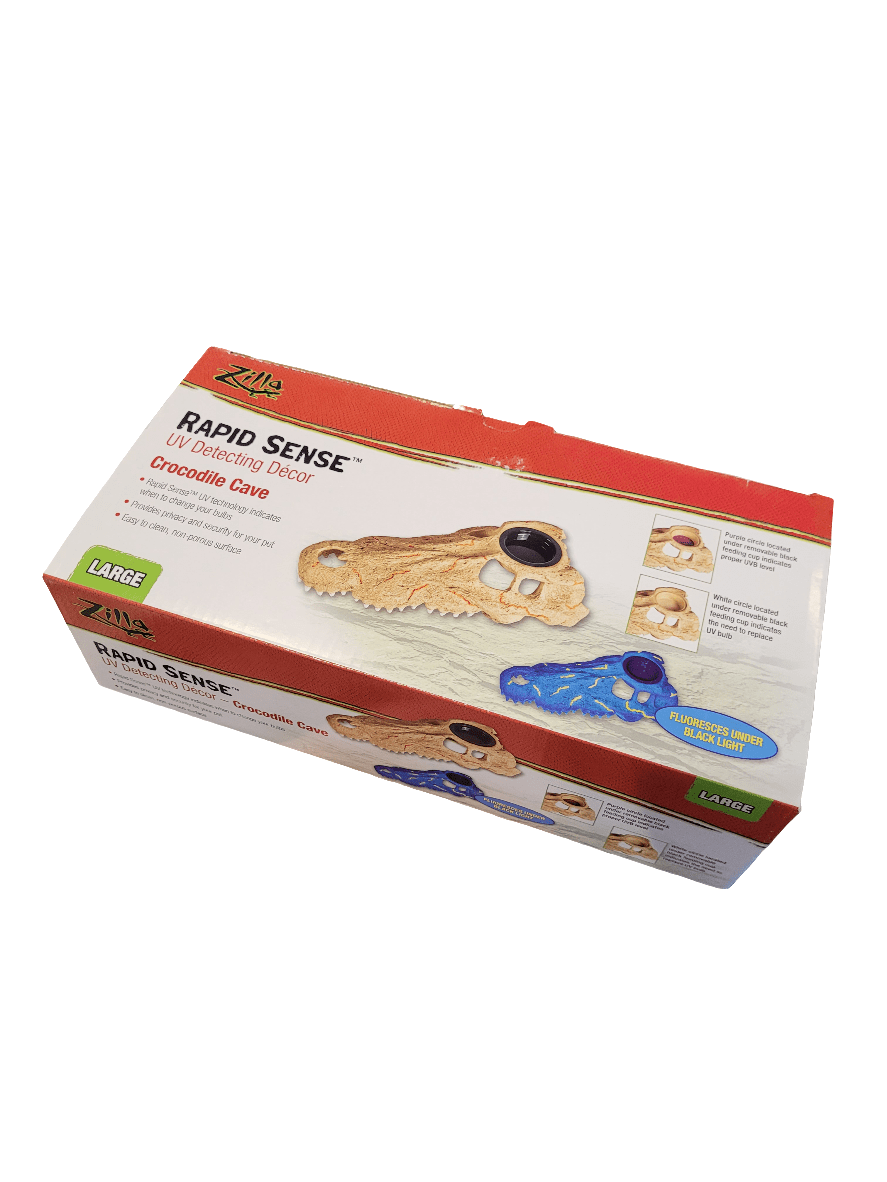 A product box for the Zilla UV Detecting Decor - Crocodile Cave - Large, featuring decals shaped like crocodile claws. The box displays beige and blue decals alongside images demonstrating their use and application. The packaging is red and white with text and logos.