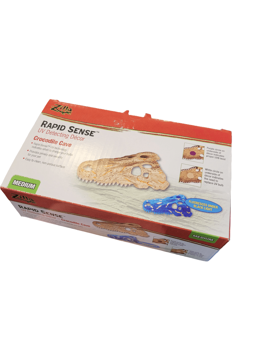 A Zilla UV Detecting Decor in the form of a Crocodile Cave, Medium size, is packaged in a box that showcases images of the cave under various lighting conditions.