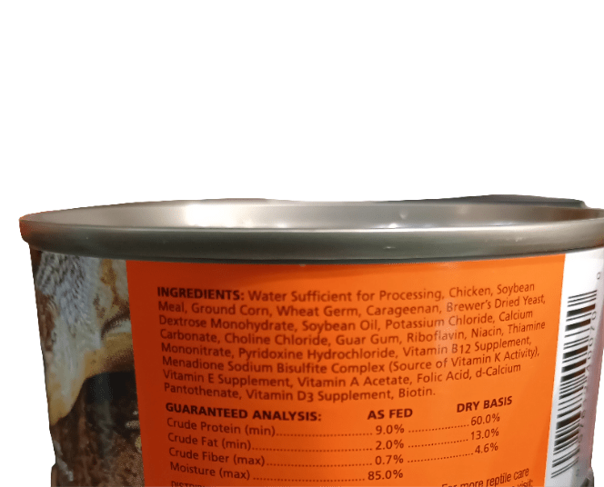 A close-up of a Zoo Med Blue Tongue Skink & Tegu Food can, showing the ingredients list. The can includes chicken, soybean meal, and various vitamins and minerals. A barcode is partially visible on the right side.