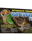 Box packaging for Zoo Med - Naturalistic Terrarium Waterfall Kit, featuring a green lizard image. Includes water pump and HydroBalls with setup instructions provided; additional items required for completion.