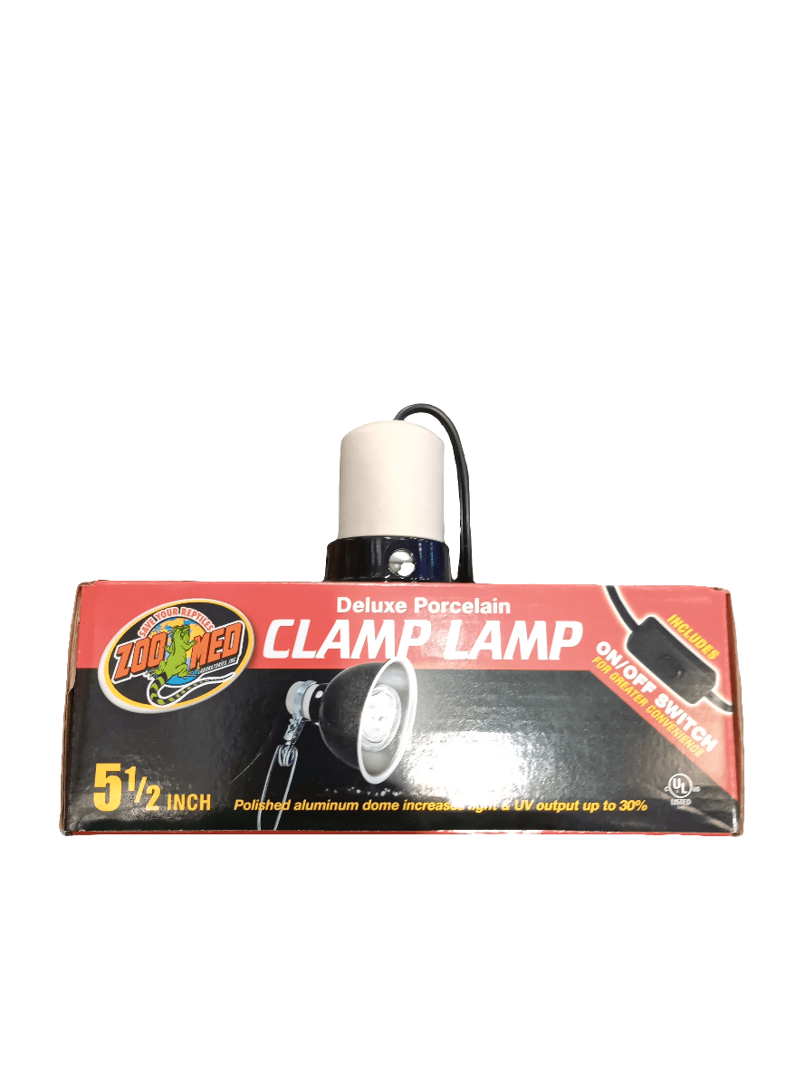 A boxed ZooMed Porcelain Clamp Lamp Black 5.5" with a polished aluminum dome and an on/off switch, featuring predominantly red and black packaging with white text and an image of the lamp.