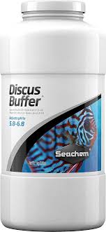 A white container of Seachem Discus Buffer with a fish image on the label is designed to lower pH and soften water, adjusting aquarium water pH to 5.8–6.8 for an ideal discus habitat.